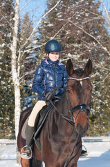 Fototapeta premium Ten years girl riding a horse in winter