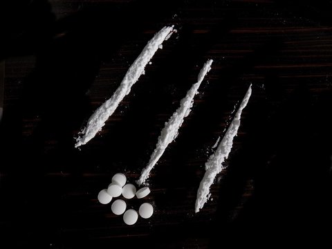 Cocaine drug powder lines and pills on black background