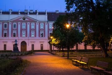 Naklejka premium Invalidovna, Karlin, Prague, Czech Republic / Czechia - park, benches, trees, lanterns and historical building made in baroque style. Dim light during evening