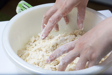 Pie with stuffing from cottage cheese and apple jam. The woman kneads the dough.