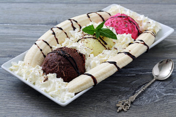 gelato misto con banana e panna montata su sfondo grigio