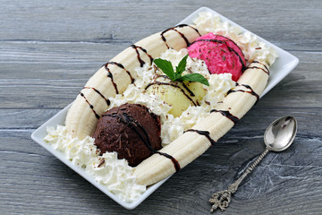 gelato misto con banana e panna montata su sfondo grigio