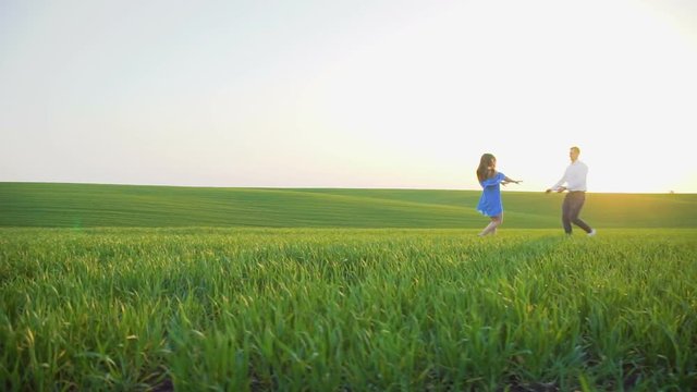 He and she running to each other and spining on the spring wheat field
