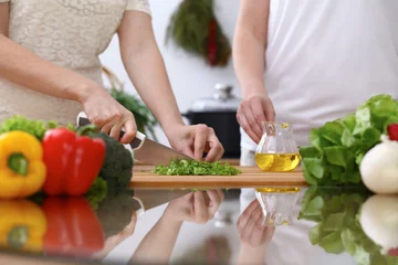 Fotobehang Closeup of two women are cooking in a kitchen. Friends having fun while preparing fresh salad © rogerphoto