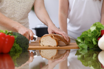 Closeup of two women are cooking in a kitchen. Friends having fun while preparing fresh salad