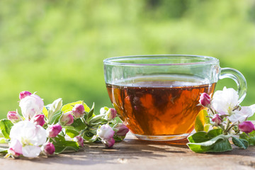 tea time/cup of tea and apple flowers on wooden table outdoors