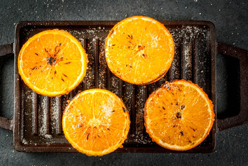 Ideas for a healthy dietary vegan breakfast. Paleo diet. Grilled oranges grapefruits. In the grill pan on a black stone table. Copy space