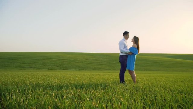 Couple in love stands in embraces, looking and kissing each other on the horizon