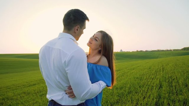 Couple in love stands in embraces, looking and kissing each other on the horizon