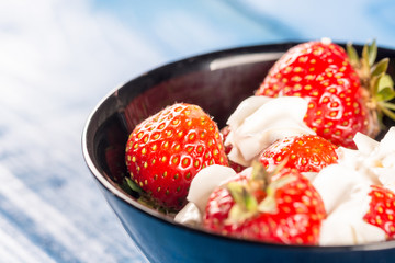 Closeup macro strawberries in white whipped cream with blue background