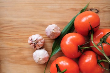 Vegetables tomatoes on the branch and garlic in wooden background