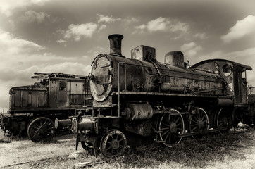 Fototapeta na wymiar Vintage looking photo of two rusty old talian steam and electric locomotives
