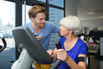 physiotherapist with senior woman using exercise machine
