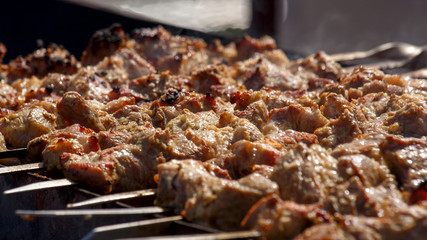 Cooking. Pork meat roasted on a spit. Meat is watered with water, creating splashes and steam. Closeup. When the aperture is wide open, selective focus.