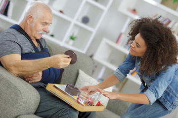 Carer serving meal to injured senior citizen