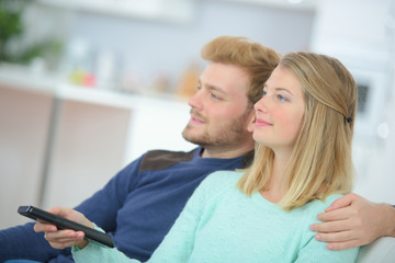 Obraz premium Embracing couple using remote control