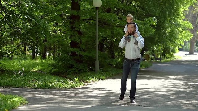 Dad and son walk in the park with a very slow gait. Father's Day.