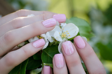 Obraz na płótnie Canvas Female hands with apple tree flowers, manicure. Close-up