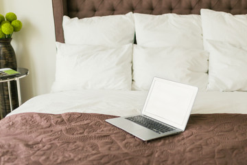 Laptop on bed with pillows. Work at home concept