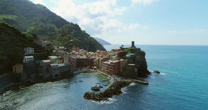 aerial view of travel landmark destination Vernazza, a small mediterranean sea town, Cinque terre National Park, Liguria, Italy. Morning sun and clouds. 4k slow motion 60 fps drone backward video shot