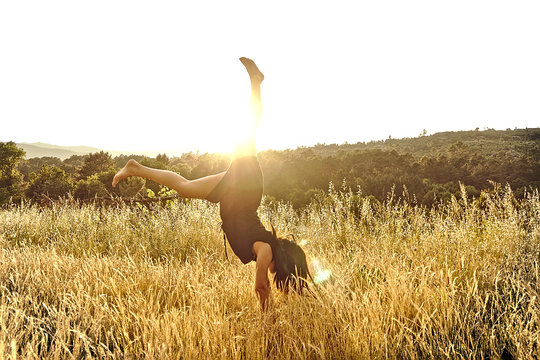 Chica levantando piernas en puesta de sol