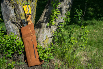 Traditional archery re-curve bow in the quiver with the arrows leaning on a tree