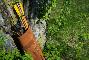 Traditional archery re-curve bow in the quiver with the arrows leaning on a tree