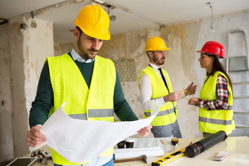 Young architect checking blueprint of  building reconstruction