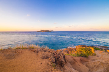 Rocky sea beach sunrise blue sky with grass