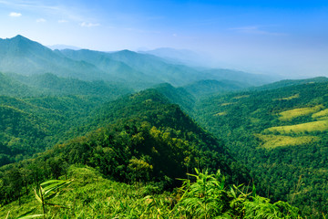 Landscape of long hill and layered mountain in the mist with blue sky.