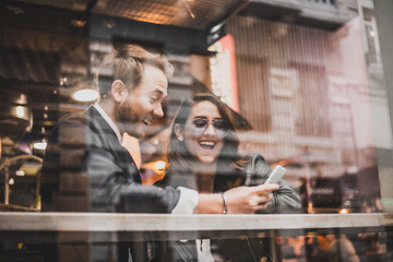 Friends using mobile in a cafe. Couple of lovers having a good time with the cell phone.