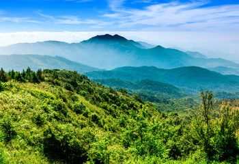 Landscape of layered mountain in the mist with dramatic blue sky.