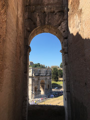Rome, Italy - 9 September 2016: Looking through an arch at the Arco Constantino (Arch of Constantine) from the Colosseum in Rome.  The triumphal arch sites between the Colosseum and Palatine Hill.