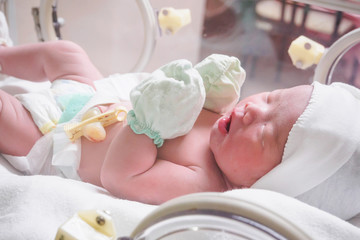Fototapeta na wymiar Newborn baby inside incubator in hospital post delivery room