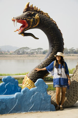 Travelers thai woman visit and posing for take photo with black naga statue at mae khong riverside