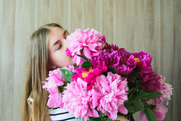 Naklejka premium Portrait of a young beautiful blonde caucasian young woman keeps bouquet pink and red peonies flowers