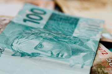 Macro closeup of a 100 Brazilian reais banknote on 50 reais notes on background