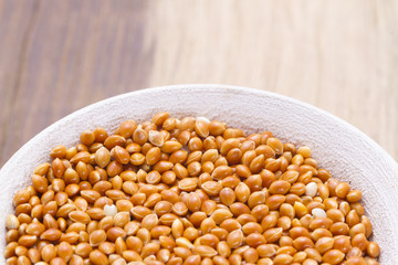 Red millet grains in bowl on wood
