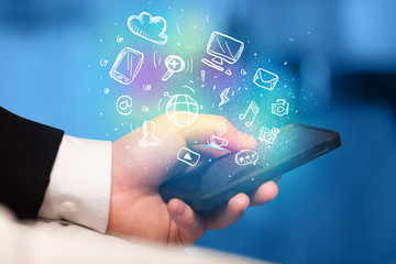 Hand holding smartphone with media icons