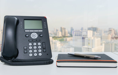 IP Phone and notebook with pen on the white office desk