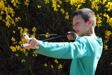 A Kid shooting slingshot on a shrub background