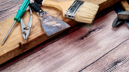 Tools for repair and construction. Spatula, brush, screwdrivers and pliers on a wooden background with space for text.