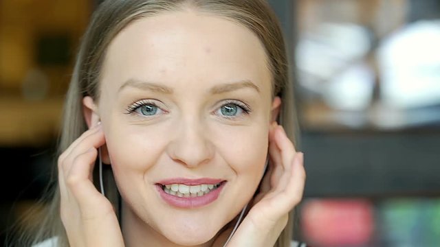 Beautiful, young girl whistles while listening music and smiling to the camera

