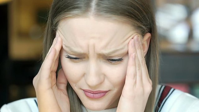 Beautiful, young girl looking upset while having migraine
