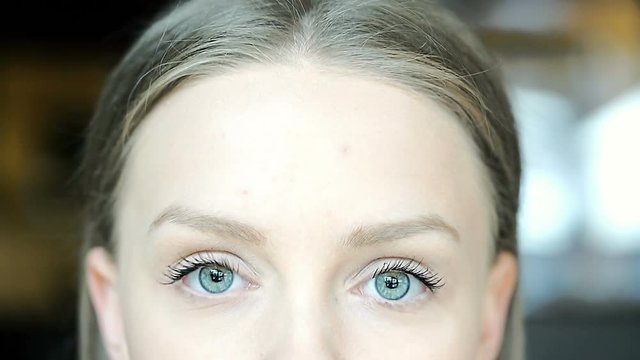 Girl with beautiful, blue eyes looking to the camera without emotions
