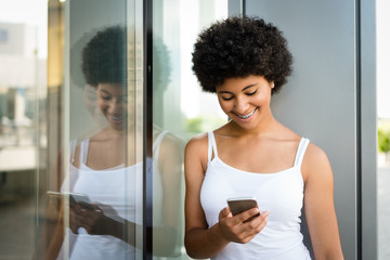 Fototapeta na wymiar Smiling teenage girl reading funny message on her smartphone