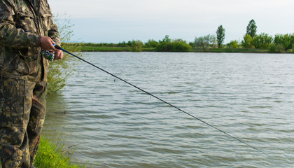 Рыбак со спиннингом на озере.