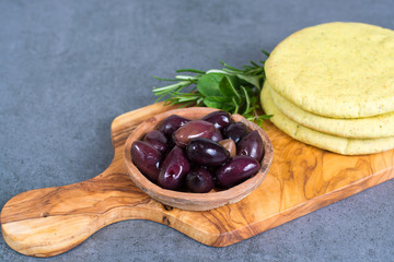 Mediterranean appetizer antipasti tapas calamara olives and garlic pita bread, herbs on wooden plank made from olive tree