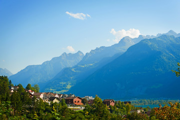 summer landscape with small houses near mountains.