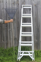 rake hanging on a wooden floor., who holds the rake, ladder aluminum.